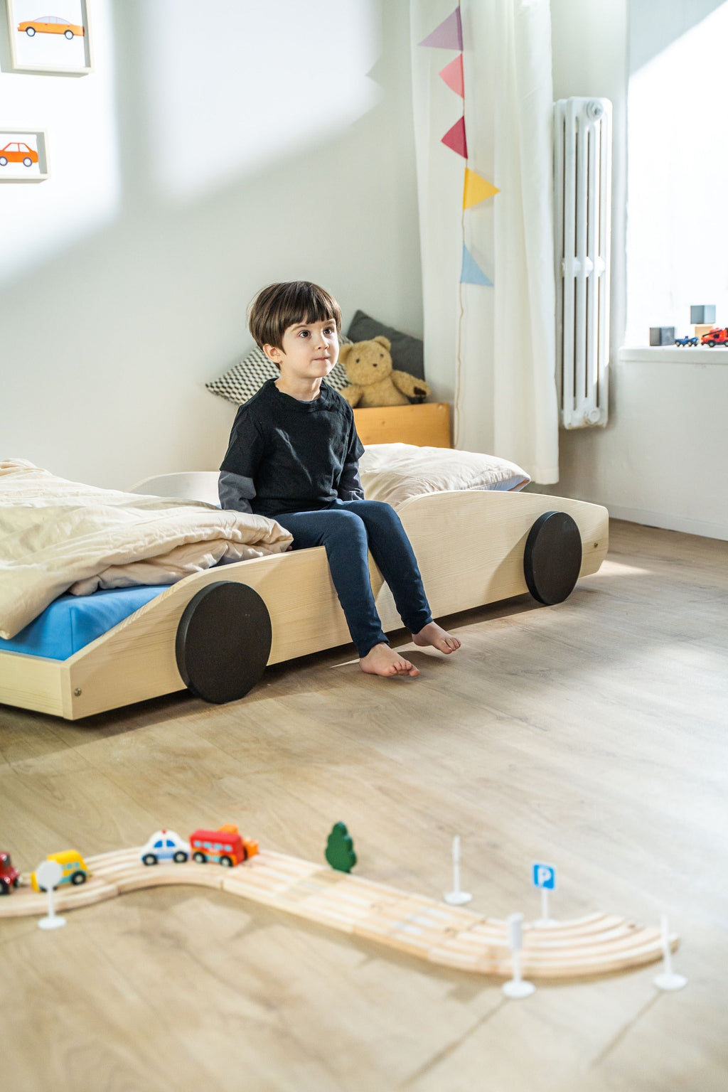 Bolide autobed in naturel hout, kind zit op de rand van het bed