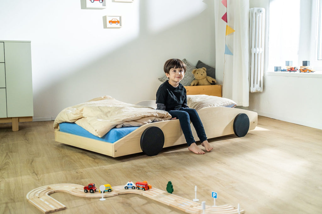 Bolide autobed in naturel hout, schuin vooraanzicht met kind op het bed