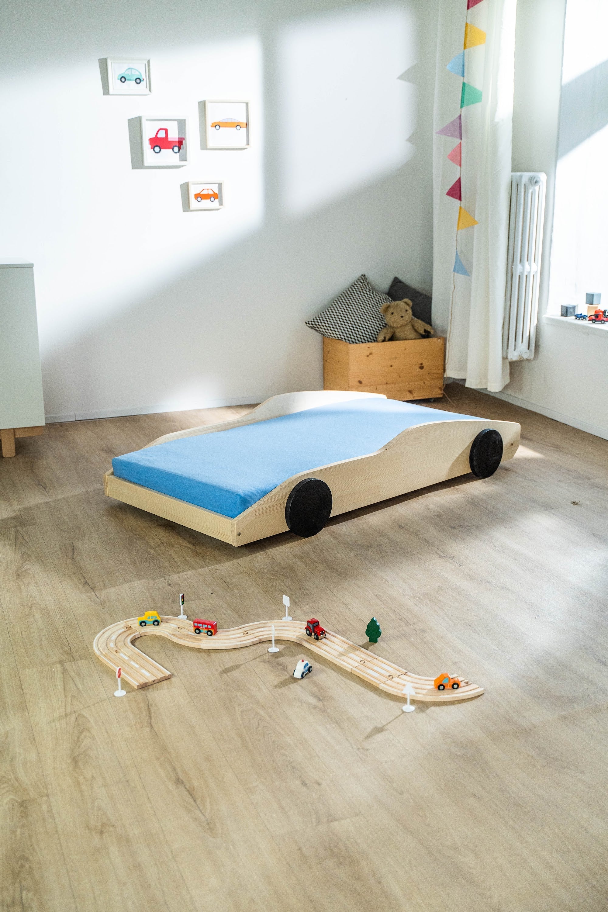Bolide autobed in naturel hout met blauwe matras in een kinderkamer met houten autobaan