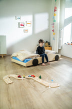 Bolide autobed in naturel hout, kind zit op het opgemaakte bed