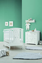 Britt babybed in wit, in een babykamer naast de bijpassende commode