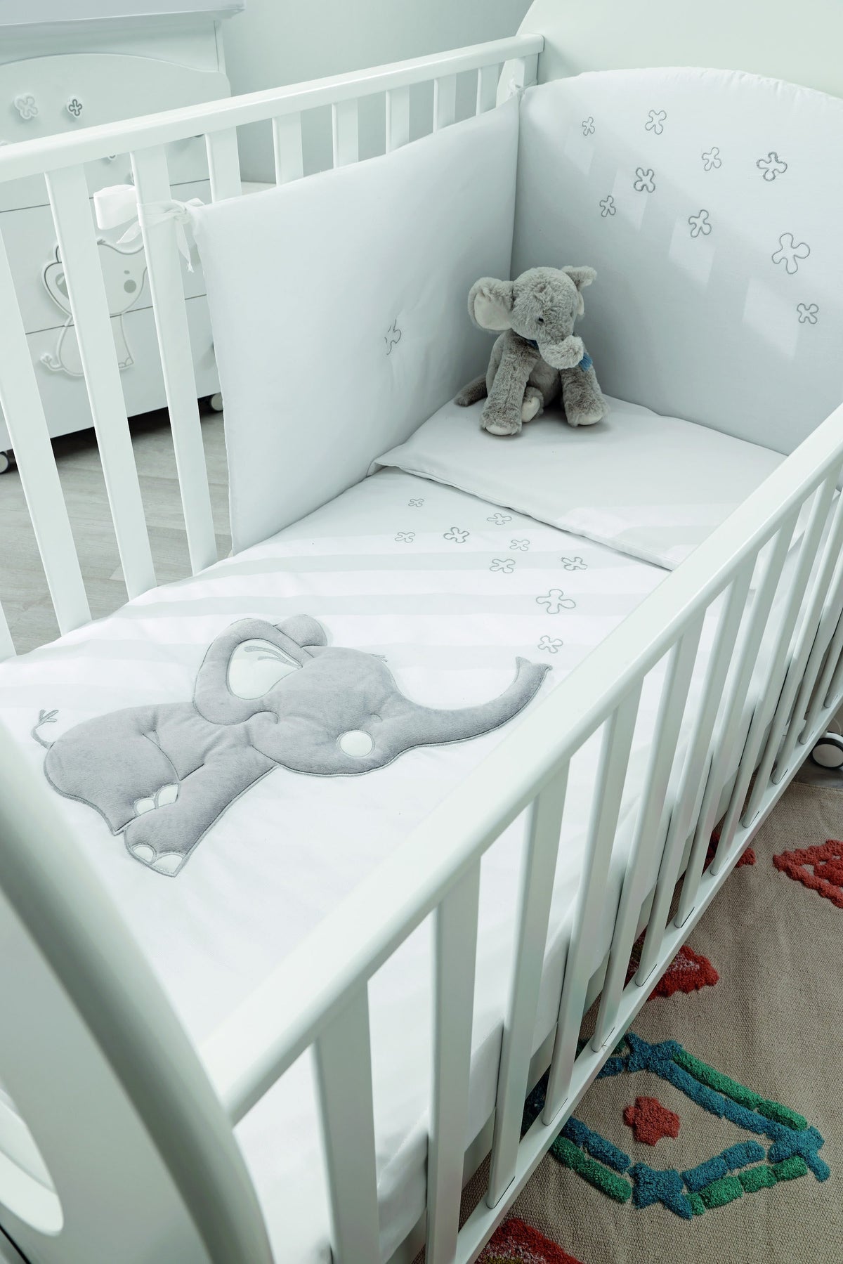 Britt beddenset in het babybed, met omranding langs de spijlen en olifantkussen