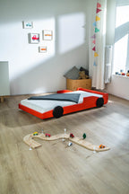 Racer autobed 80×160 in rood, schuin achteraanzicht in een kinderkamer met houten autobaan