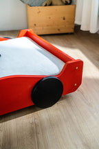 Racer autobed 80×160 in rood, close-up van de voorzijde met zwart wiel
