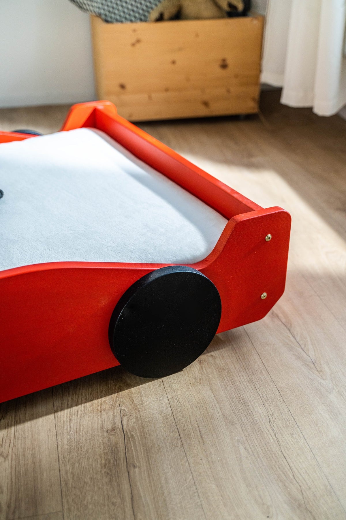 Racer autobed 80×160 in rood, close-up van de voorzijde met zwart wiel