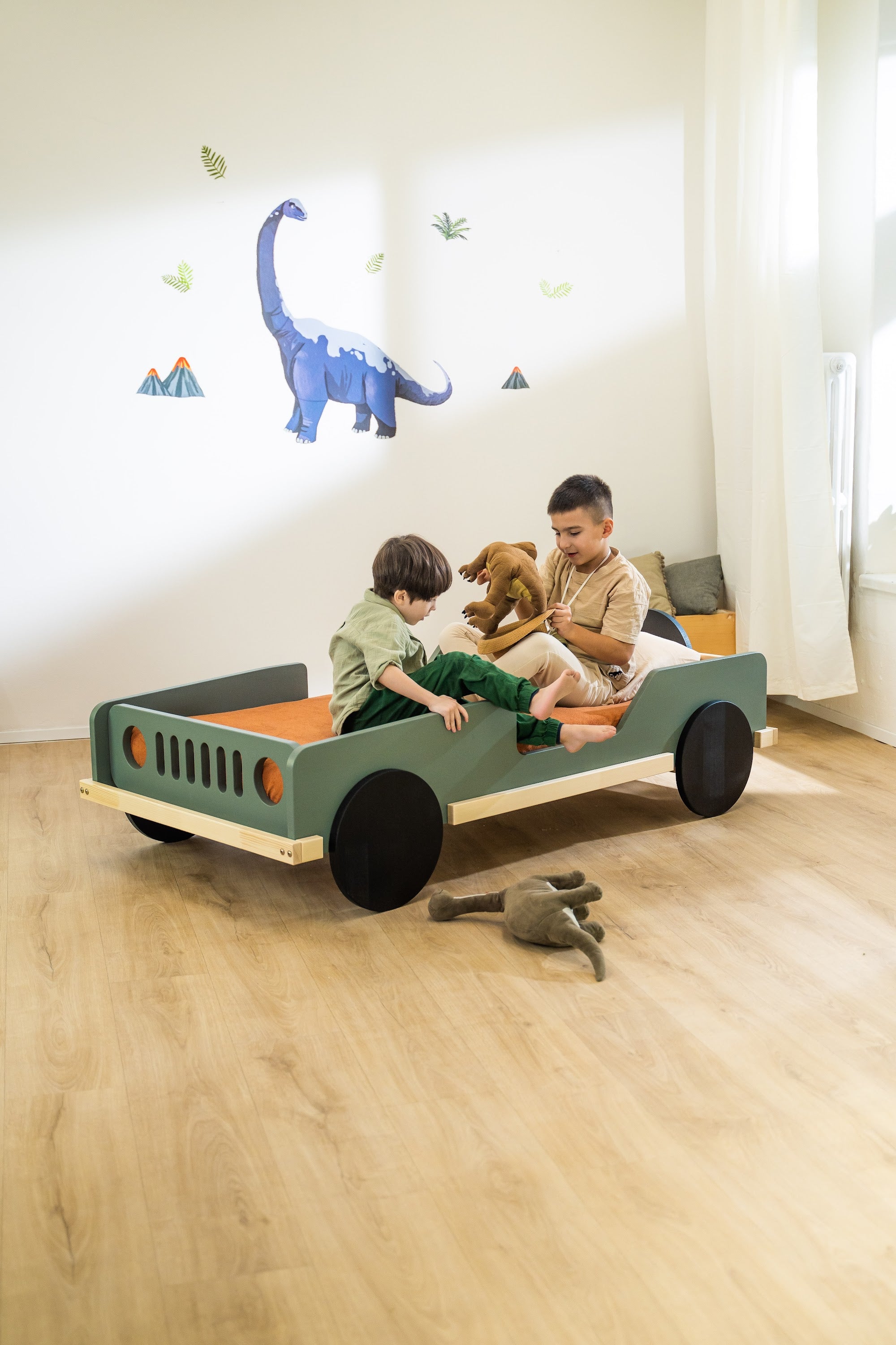 Scout autobed 80×160 in saliegroen, twee kinderen zitten op het bed