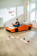 Turbo GT autobed 80×160 in oranje in een kinderkamer, kind zit op het bed