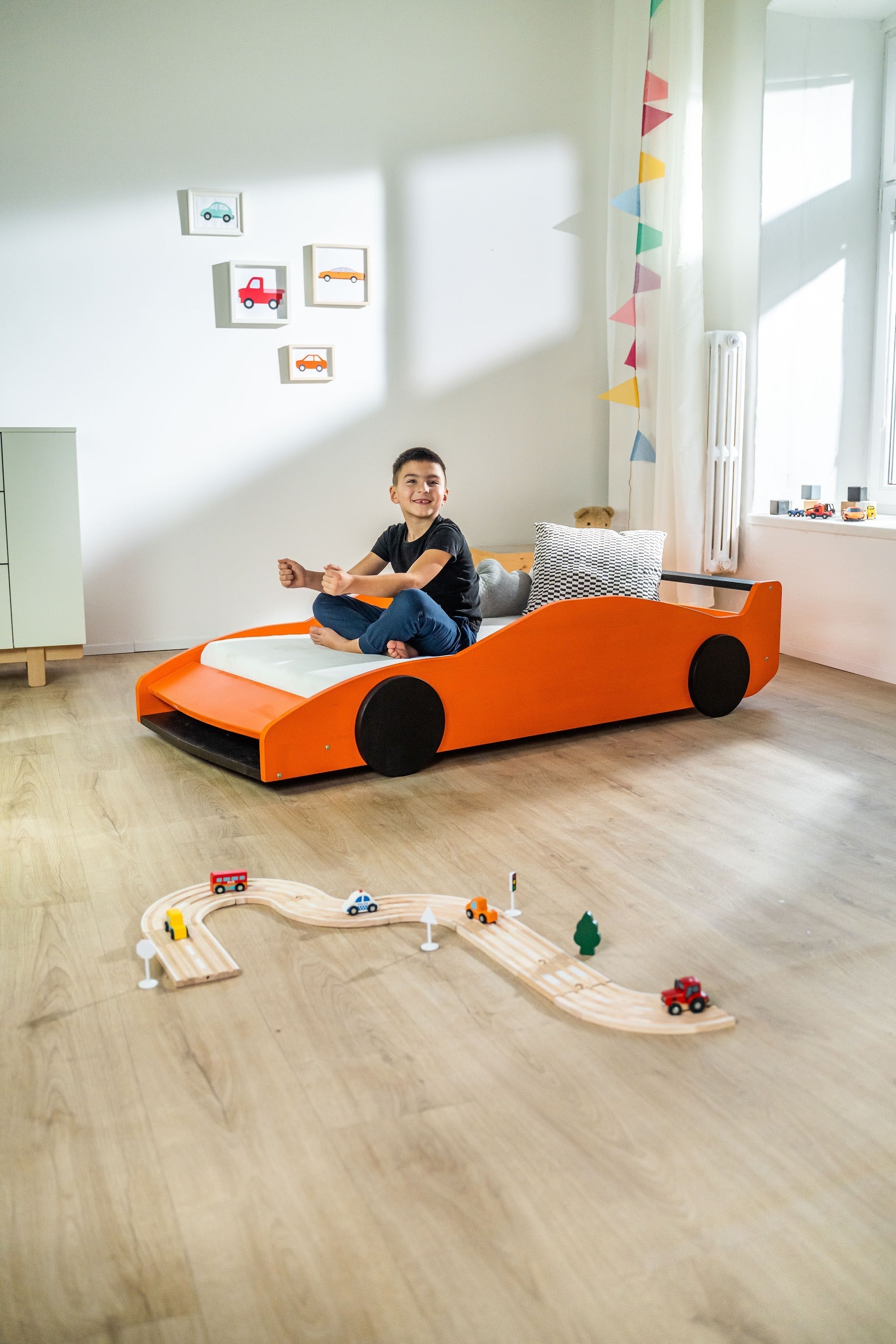 Turbo GT autobed 80×160 in oranje in een kinderkamer, kind zit op het bed
