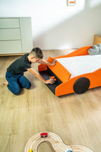 Turbo GT autobed 80×160 in oranje, kind speelt bij het opbergvak van het bed