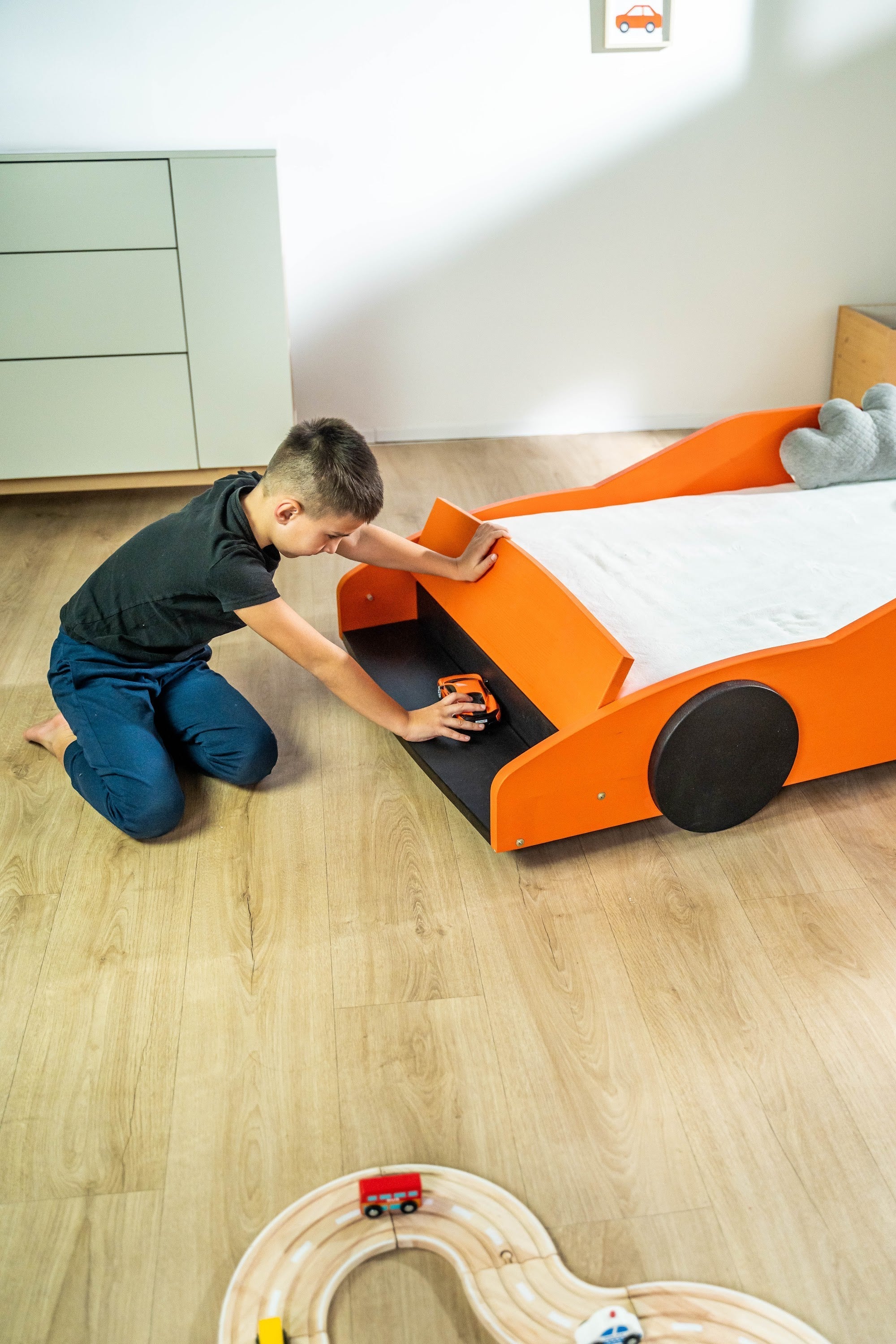 Turbo GT autobed 80×160 in oranje, kind speelt bij het opbergvak van het bed